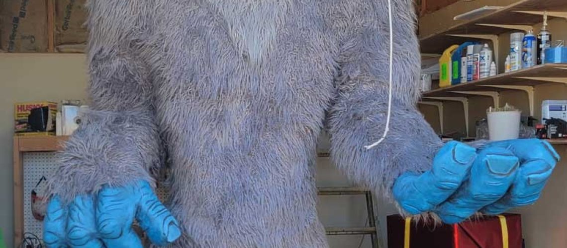 An approximately 10 foot tall 3D foam sculpture of a friendly looking blue skinned yeti with grey fur.